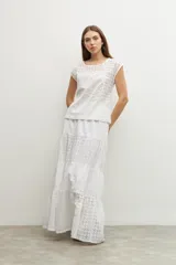 Blusa blanca con bordado calado, de corte recto y mangas cortas.