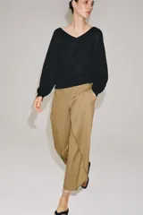 Pantalón de tiro medio confeccionado en mezcla de lyocell, con diseño de pliegues delanteros superpuestos y bolsillos laterales ocultos en costura.