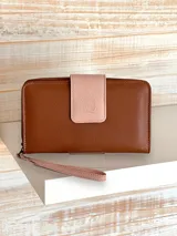 Billetera grande de cuero color marrón con solapa rosa y cierre de cremallera. Incluye correa de mano extraíble.