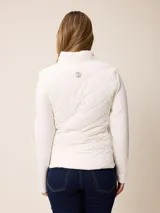 Campera acolchada con frente y espalda en tejido técnico, combinada con mangas y laterales de tejido liso. Presenta cuello alto, cierre frontal completo y bolsillos laterales. Incluye un pequeño detalle bordado en el pecho.
