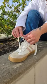 Zapatillas Dallas de cuero blanco, con detalles en gamuza beige y tiras laterales rosadas, suela de goma y diseño urbano.