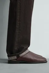 Zueco de piel color marrón oscuro, con diseño liso, horma cuadrada y suela con ligero tacón.