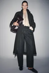 Pantalón de tiro medio con diseño balloon, confeccionado en tejido con patrón de rayas verticales. Presenta cintura con trabillas, cierre frontal con cremallera y botón, y cinco bolsillos.