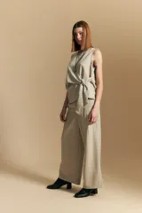 Pantalón ancho de tiro alto, color blanco roto con finas rayas verticales en color beige/marrón. Presenta un detalle de nudo o lazo en la cintura.