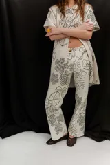 Pantalón de gabardina elastizada color crudo con estampado gráfico floral en color negro, de corte recto.