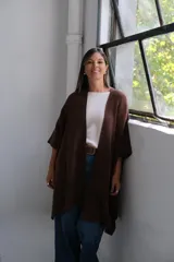 Poncho abierto de color marrón chocolate, con diseño de corte asimétrico, mangas amplias y bolsillos frontales aplicados.