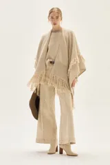 Pantalón de jean color beige claro, tiro alto, de corte ancho (wide leg) y largo hasta el tobillo con dobladillo. Presenta costuras verticales marcadas en el frente de las piernas.