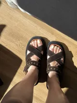 Sandalias de cuero marrón con textura de cocodrilo, diseño de tiras cruzadas con tachas metálicas plateadas y suela track negra de plataforma.