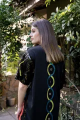 Vestido corto negro de lentejuelas con diseño de letras multicolores.