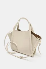 Bolso bandolera de formato city color marrón, con diseño estructurado, pespuntes decorativos, doble asa de mano y cremalleras laterales con tiradores colgantes.