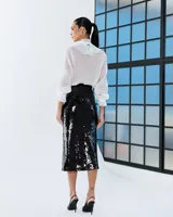 Camisa de color blanco off-white con volados frontales, mangas largas con puños ajustados y cuello redondo, confeccionada en tela fluida.