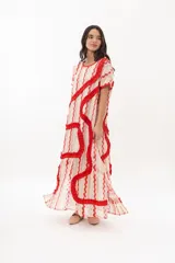 Vestido largo tipo remerón con estampado a rayas verticales en tonos beige, rosa y rojo. Presenta escote redondo y volados rojos en forma de espiral.