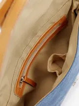 Cartera tipo bandolera de jean azul con ribetes y detalles de cuero tostado, asa de hombro y solapa frontal con cierre magnético y trabilla central.