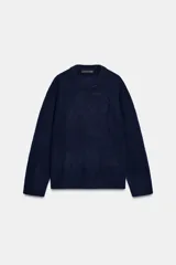 Jersey de punto liso color azul marino, con cuello redondo y manga larga. Acabados en rib.