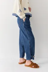 Jean de corte gaucho en color azul, con diseño de pinzas en la cintura, tiro medio y detalle de ajuste con botón en el ruedo.