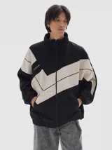 Campera de denim con diseño color block en negro y beige, corte oversized, cuello alto, cierre frontal completo, bolsillos laterales con cierre y puños y cintura elásticos.