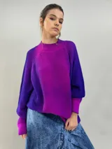 Buzo tejido de lana merino con diseño oversize, manga ranglan y cuello levemente elevado. Presenta un degradado de color vibrante en tonos violeta y fucsia.