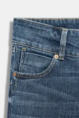 Jeans de tiro bajo y cintura ancha, con diseño bootcut de corte evasé desde la rodilla. Cuenta con cinco bolsillos y cierre frontal con cremallera y dos botones metálicos. Color azul con efecto desgastado.