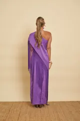 Vestido largo morado de un solo hombro, con detalles bordados florales en tono crudo y un gran mantón con flecos largos del mismo color.