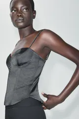 Top de satén negro estilo corsetero, con escote corazón, tirantes finos ajustables y cierre frontal con ganchos metálicos.