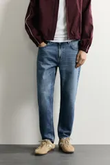 Jeans de corte slim cropped confeccionados en denim de algodón rígido con efecto lavado. Presentan tiro medio, cierre frontal con cremallera y botón, y diseño clásico de cinco bolsillos.