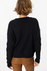 Sweater de punto negro con diseño de trenzas verticales en el frente y cuello redondo. Presenta un corte holgado con puños y ruedo acanalados.