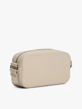 Cartera tipo bandolera Tommy Jeans de diseño compacto y acabado liso en color beige. Cuenta con cierre de cremallera superior y una insignia metálica distintiva de la marca en la parte frontal.