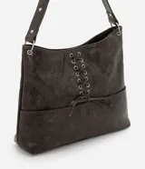 Cartera estilo hobo de cuero sintético en color gris oscuro, con diseño de media luna y correa fija para el hombro. Cuenta con bolsillos frontales funcionales, detalles de ojalillos metálicos plateados y un cordón cruzado ajustable con lazo en el centro.