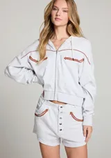 Campera gris con capucha, cierre frontal y detalles de flechas marrones en el pecho y los hombros.