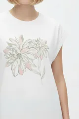 Remera negra de algodón, con cuello redondo, mangas cortas holgadas con vuelta y estampa floral grande en el pecho.
