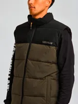Chaleco puffer Caterpillar Arctic Zone Vest, modelo bicolor con parte superior negra y parte inferior en verde militar, cuello alto y cierre frontal con cremallera.