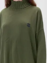 Pullover de punto color rojo, con cuello tortuga, corte holgado y mangas largas con puños acanalados en contraste con rayas blancas. Presenta un logo bordado en el pecho.