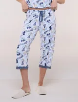 Conjunto pijama de pantalón capri y remera René Rofé, de color blanco con estampado floral en tonos azules y celestes. Remera de manga corta con escote en V y detalles de encaje azul en el escote, las mangas y el ruedo. Pantalón capri con cintura elastizada, cordón de ajuste y encaje en el ruedo.
