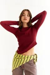 Top de manga larga color blanco, confeccionado en tejido de punto acanalado con diseño irregular y aberturas para los pulgares en los puños.