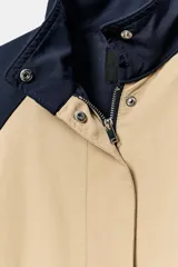 Cazadora combinada de nylon en color azul marino y beige, con cuello alto, cierre frontal oculto y bajo ajustable con cordón.