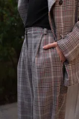 Pantalón sastrero de tiro alto con estampa a cuadros en tonos grises, rojos y blancos, de corte recto y holgado.