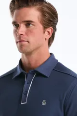 Sweater de punto con textura tipo waffle, color azul, con cuello polo, cierre frontal parcial con botones y detalles de ribete en contraste. Presenta mangas largas con puños elásticos y logo bordado en el pecho.