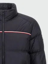 Campera puffer de corte regular, color azul marino, con cuello alto, cierre frontal completo y detalle de franja tricolor en el pecho. Cuenta con bolsillos laterales con cierre y puños elásticos.