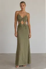 Vestido largo verde militar de tirantes finos, con aberturas en la cintura y detalles de flecos en el corpiño y la cadera.