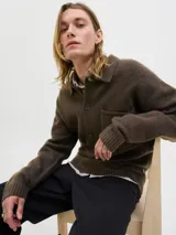 Cardigan de punto color marrón oscuro, con cuello tipo polo, cierre frontal con botones y un bolsillo aplicado en el pecho. Presenta mangas largas con hombros caídos y puños acanalados.