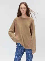 Remera de manga larga con efecto desgastado, cuello redondo y costuras expuestas en color contrastante. Presenta un diseño holgado con detalle de logo bordado en el ruedo.