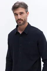 Camisa de manga larga color azul marino, confeccionada en algodón con textura, cuenta con un bolsillo frontal y cierre frontal con botones.