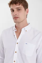 Camisa de vestir blanca de manga larga, con cuello abotonado, bolsillo frontal y botones en tono madera.