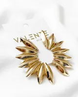Aros dorados con forma de flor, con pétalos alargados y puntiagudos.