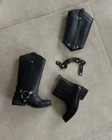 Bota de cuero negra con caña alta y estribo desmontable.