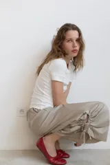 Pantalón tipo culotte de tiro medio con cintura elástica y bolsillos laterales ocultos. Presenta un diseño de pernera ancha con aberturas laterales en el bajo, ajustables mediante cordones con frunces.