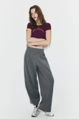 Pantalón de tiro alto con diseño de rayas verticales, corte recto y holgado. Presenta pliegues frontales, bolsillos laterales y bajo ajustable con botón.