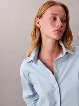 Camisa de corte clásico con estampado de rayas verticales en tonos celeste y amarillo. Presenta cuello en punta, mangas largas con hombros caídos y cierre frontal mediante botones.