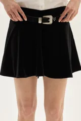 Falda corta de terciopelo negro con diseño ajustado en la cadera y volado en el ruedo.