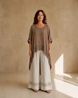 Blusa de lino color camel, con diseño asimétrico de corte más largo en la espalda, escote redondo y mangas tres cuartos con trabilla y botón. Presenta un detalle de tejido calado en el ruedo inferior.